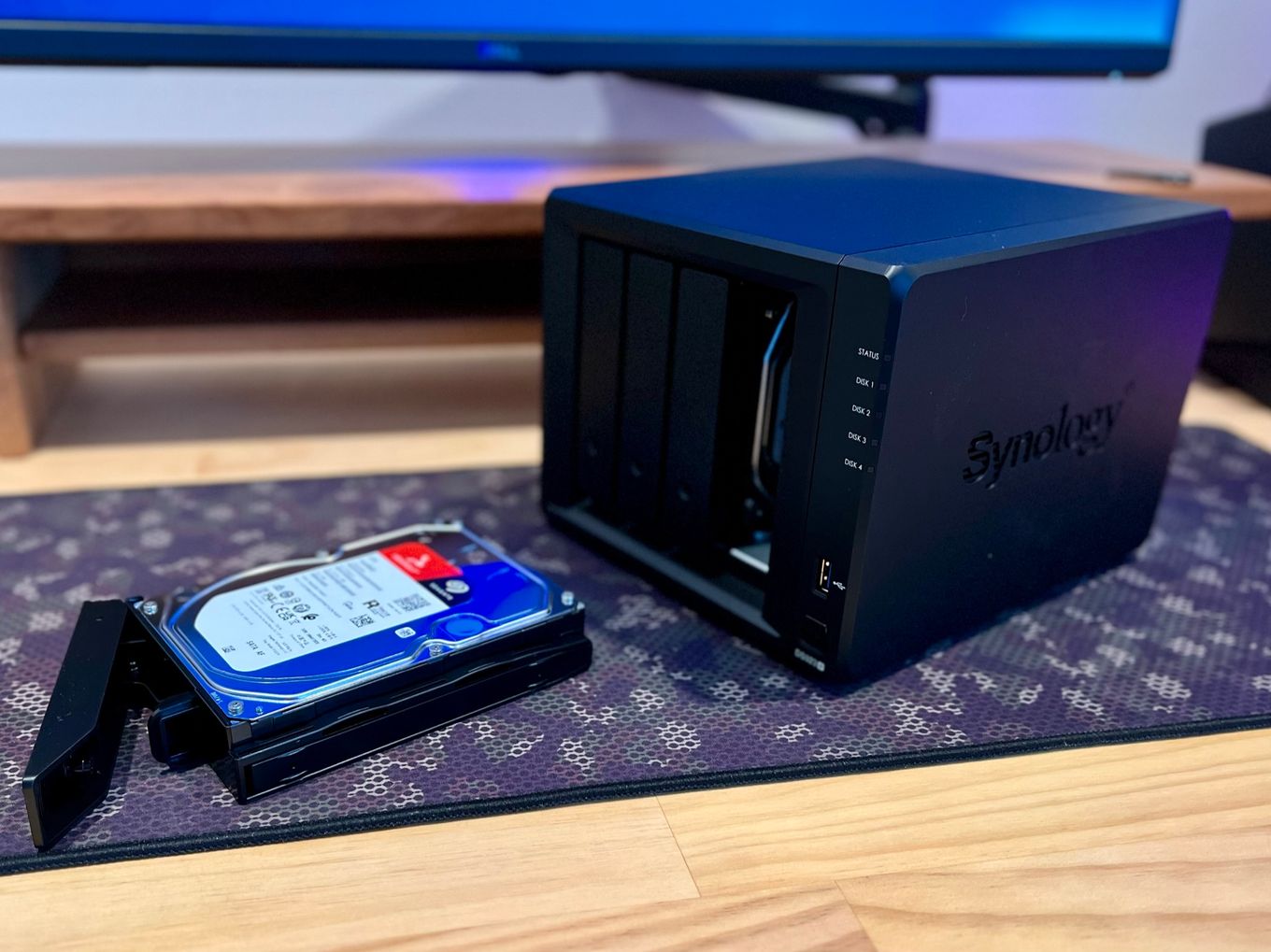 A photo of a Synology DS923+ NAS device sitting on a computer desk with a 8TB harddrive about to be installed.