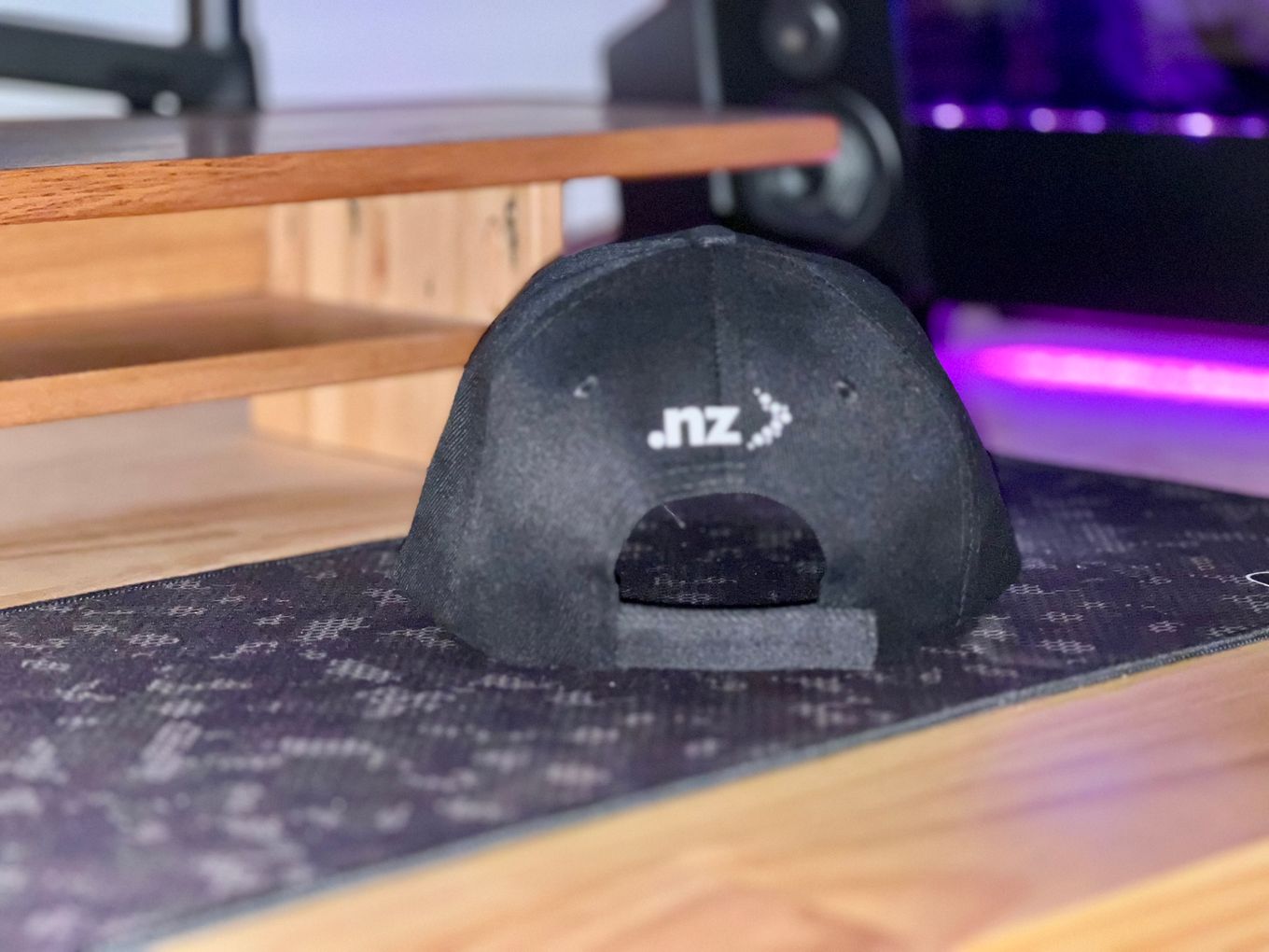A black hat with InternetNZ branding sitting on top of a wooden table.