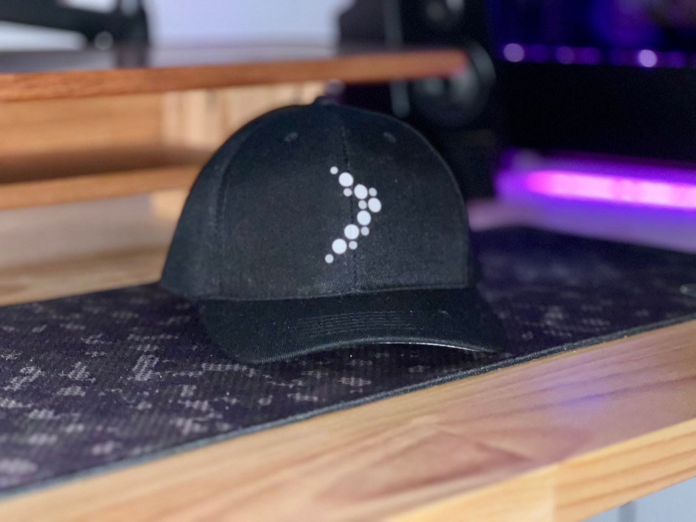 A black hat with InternetNZ branding sitting on top of a wooden table.