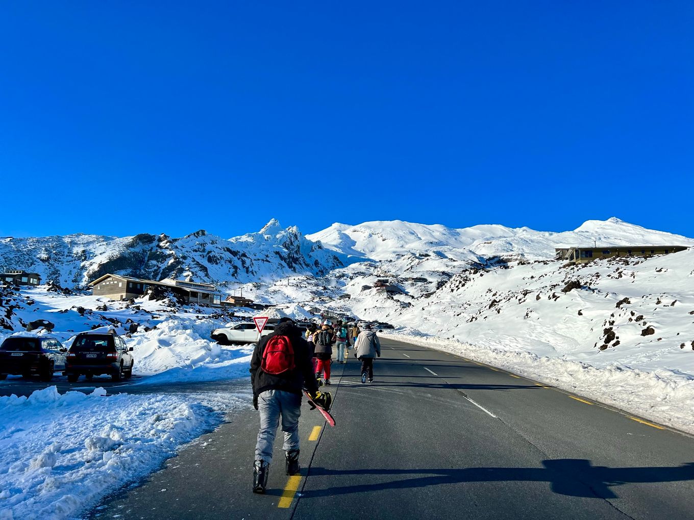 a group of people walking up a snow covered road towards the Whakapapa ski field.