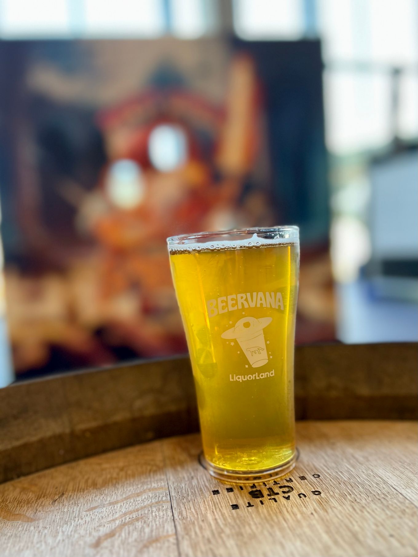 a glass of beer sitting on top of a wooden barrel